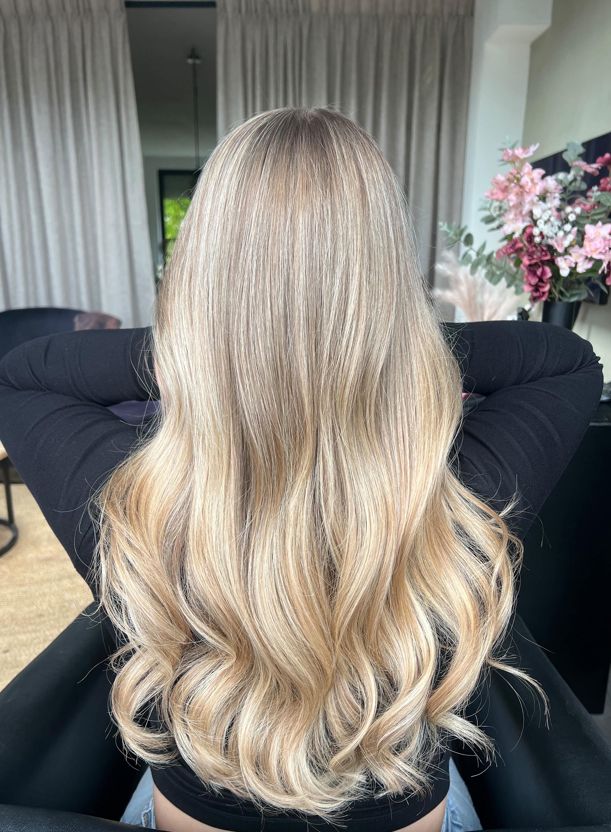 Lang blond haar met balayage in golven, van achteren gezien